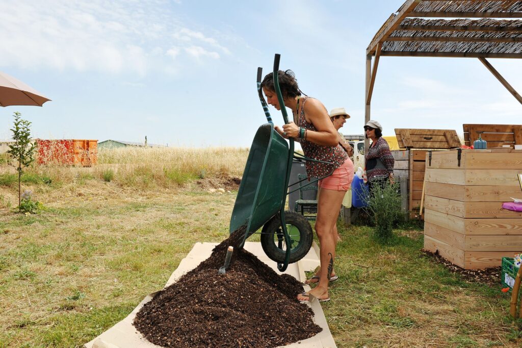 Brouette remplie de compost brun grumeleux &agrave; c&ocirc;t&eacute; d'un bac de culture vid&eacute;