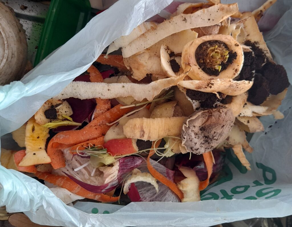 Bol rempli d'&eacute;pluchures de l&eacute;gumes coup&eacute;es en petits morceaux sur un plan de travail