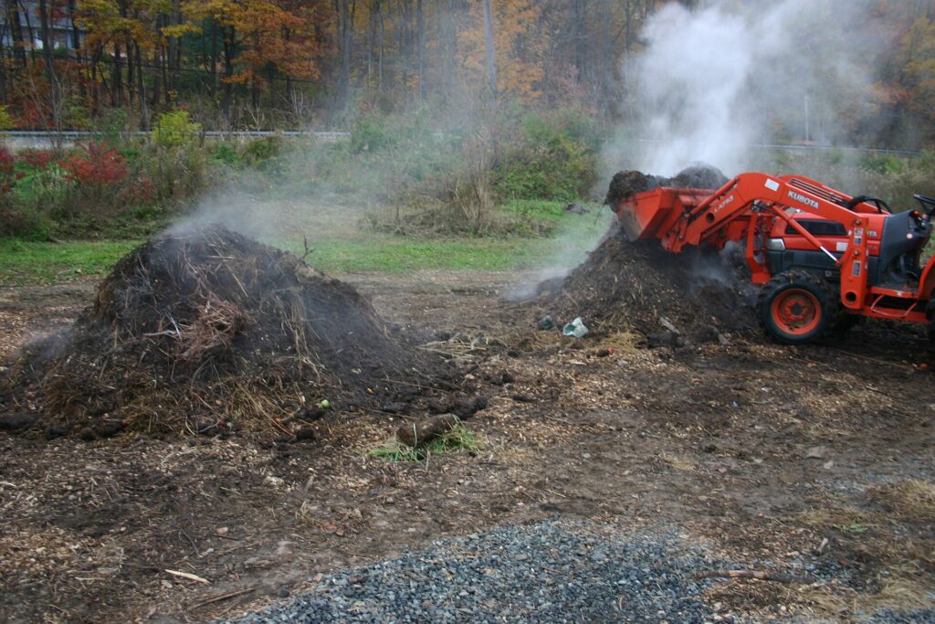Compost m&ucirc;r brun fonc&eacute; et friable retourn&eacute; &agrave; la fourche dans un composteur en bois